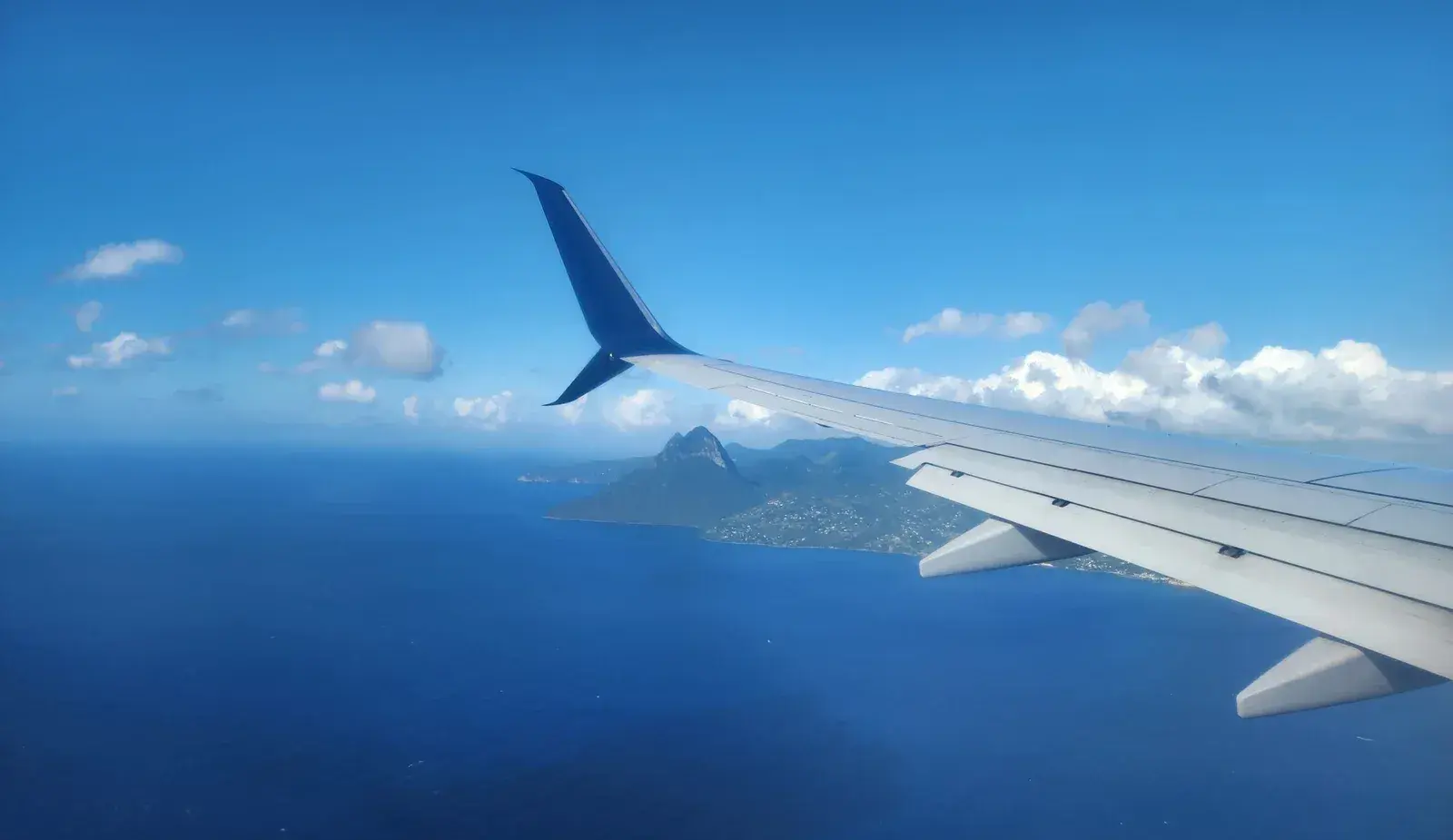 A wing of a plane flying over St Lucia.